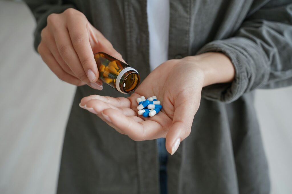 Drug addiction. Hand of african american girl or young woman holding medicine drugs and and flacon.